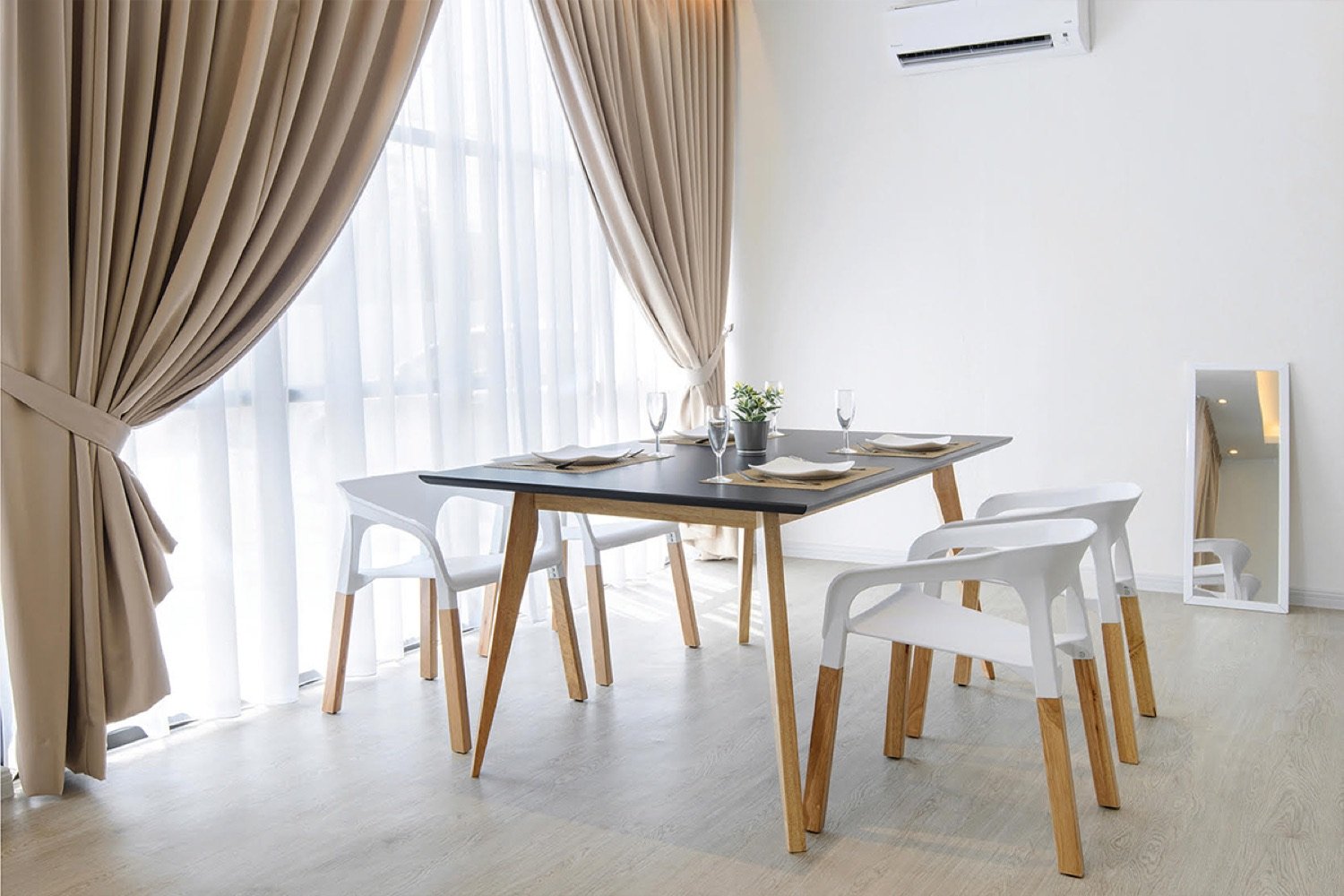 A warm dining room with Century chairs around a wooden table and soft daylight through linen curtains