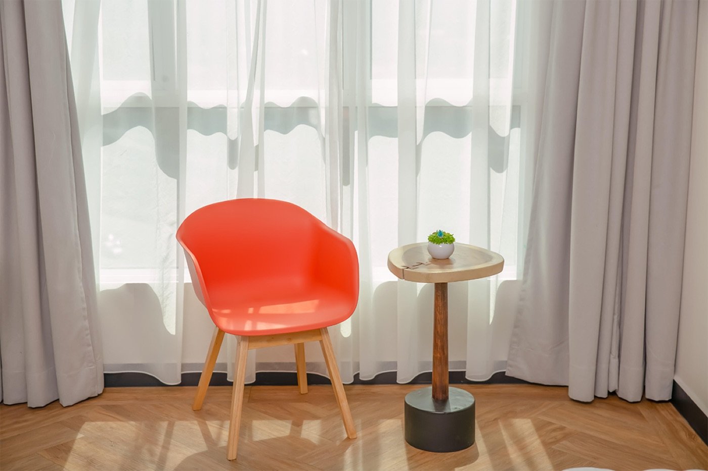 A bright orange Century chair beside a small side table in a sunlit room