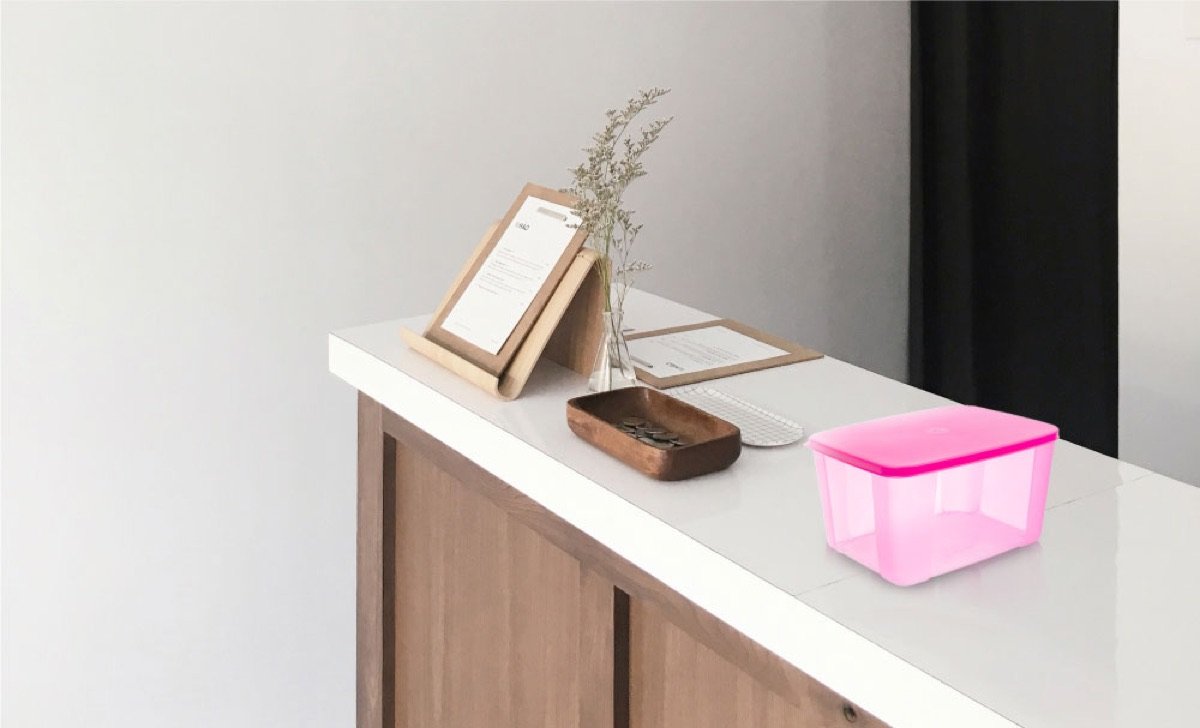 A translucent pink Century storage box on a white worktop with warm wooden cabinetry